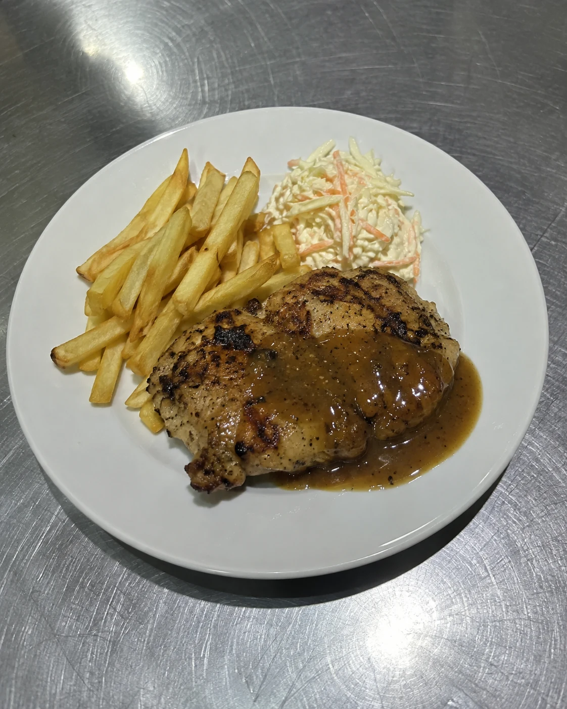 An ordinary phone photo of chicken chop on a stainless-steel kitchen counter